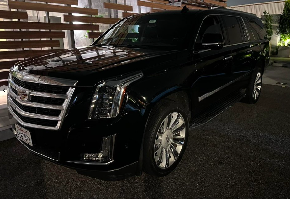 Black Cadillac Escalade waiting at an evening venue entrance